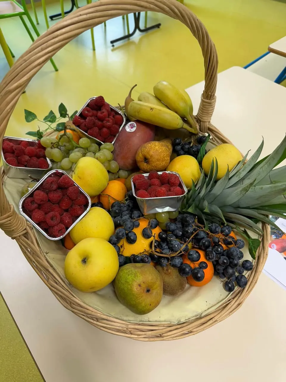 Corbeille de fruits frais : framboises, raisins, pommes, poires et ananas